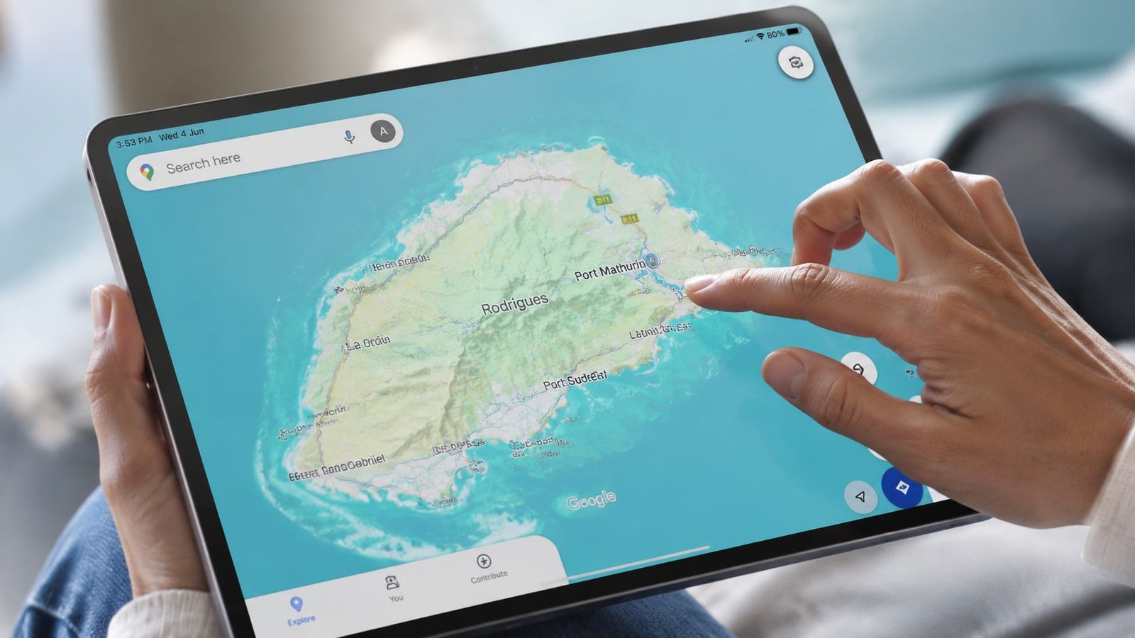 A person holding a tablet displaying a detailed Google Maps view of Rodrigues island.